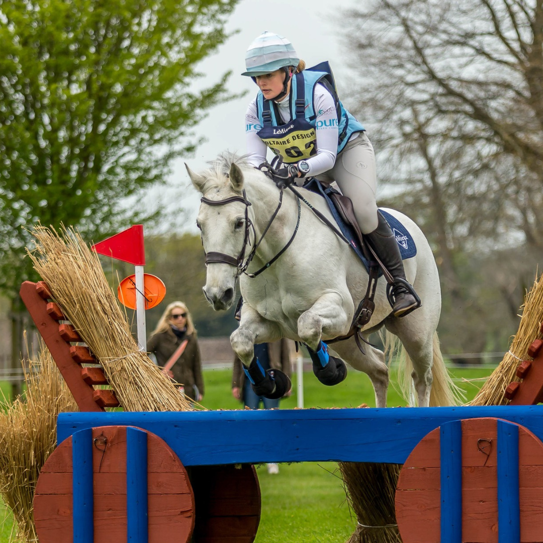 Meg Elphick jumping a hay cart at Badminton Grassroots, wearing her Point Two air vest in baby blue.